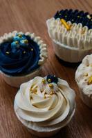 Luxurious and elegant cupcakes, with white cream and navy blue with gold sprinkles. photo