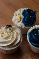 Luxurious and elegant cupcakes, with white cream and navy blue with gold sprinkles. photo