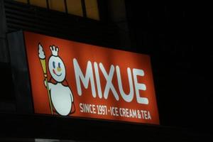 Bekasi, Indonesia on July 2022. Glowing MIXUE restaurant sign against night sky. photo