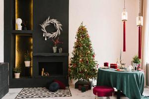 Stylish luxurious interior of the dining room with a Christmas tree. A chair near a round table and a fireplace. Classic modern house photo