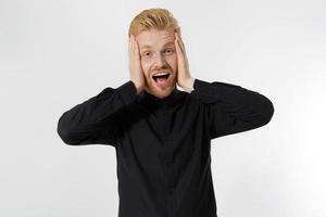 emocionado sorprendido shock joven gritando hombre aislado sobre fondo gris. chico pelirrojo feliz con barba roja en camisa negra elegante. éxito y aprobar el concepto de examen. copie el espacio. primer plano de la expresión de la cara. foto