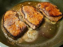 a freshly fried beef steak from the frying pan with delicious ingredients photo