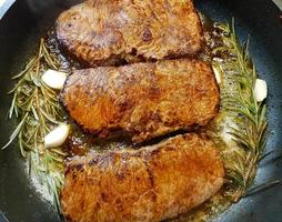 a freshly fried beef steak from the frying pan with delicious ingredients photo