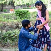 Indian couple posing for maternity baby shoot. The couple is posing in a lawn with green grass and the woman is falunting her baby bump in Lodhi Garden in New Delhi, India photo