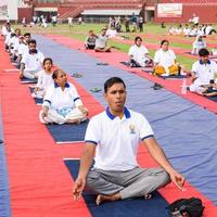 New Delhi, India, June 21 2022 - Group Yoga exercise session for people at Yamuna Sports Complex in Delhi on International Yoga Day, Big group of adults attending yoga class in cricket stadium photo