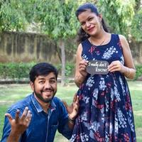 Indian couple posing for maternity baby shoot. The couple is posing in a lawn with green grass and the woman is falunting her baby bump in Lodhi Garden in New Delhi, India photo