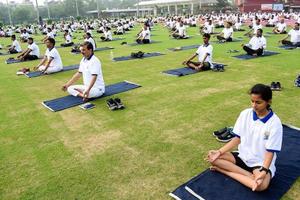 nueva delhi, india, 21 de junio de 2022 - sesión grupal de ejercicios de yoga para personas en el complejo deportivo yamuna en delhi el día internacional del yoga, gran grupo de adultos que asisten a clases de yoga en el estadio de cricket foto