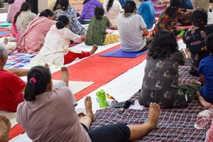 New Delhi, India, June 19 2022 -Group Yoga exercise session for people of different age groups in Balaji Temple, Vivek Vihar, International Yoga Day, Big group of adults attending yoga class in temple photo