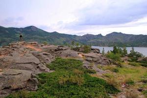 Travel to Kazakhstan, Bayanaul National Park. The young man is walking near a lake and mountains. photo