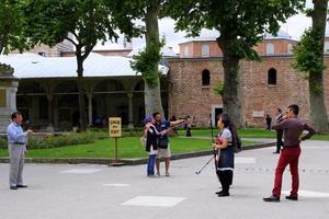 ISTANBUL, TURKEY - JUNE 22, 2015. Tourists with cameras, mobile phones and selfie sticks are taking photos near to Topkapi Palace.