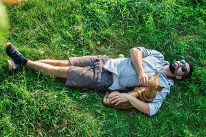 Top view of man and dog lying on green grass. Attractive European man is hugging his dog. photo