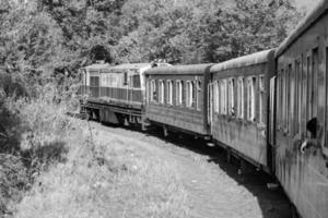 tren de juguete moviéndose en la ladera de la montaña, hermosa vista, montaña de un lado, valle de un lado moviéndose en ferrocarril a la colina, entre bosques naturales verdes.tren de juguete de kalka a shimla en india-blanco y negro foto