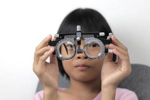 niña sosteniendo anteojos de montura de prueba foto