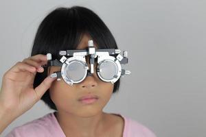 niña con anteojos de marco de prueba, concepto de prueba ocular foto