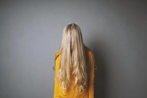 mujer joven deprimida escondiendo su rostro detrás del pelo largo y rubio foto