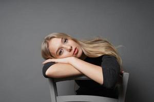 bored young woman sitting astride on chair with head resting on backrest photo