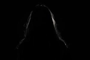 anonymous woman hiding face and identy in the dark shadow photo