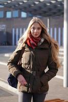 Retrato de moda de estilo callejero de mujer joven esperando en la estación de autobuses foto