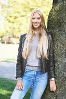 young woman leaning against tree in park photo