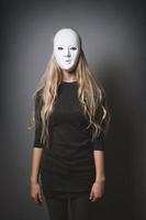 mysterious woman hiding face and identity behind white mask photo