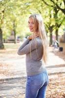 rear view of young woman wearing jeans and sweater turning head around