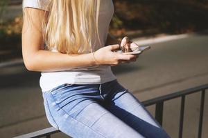 unrecognizable young woman using smartphone mobile outside on city street photo