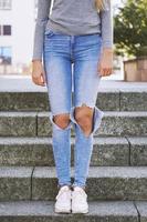 distressed denim ripped jeans with holes exposing knees of girl photo
