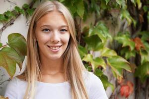 mujer joven sonriente contra la pared revestida de hiedra foto