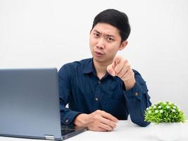 Man sitting at the table with laptop and point finger at you serious emotion photo