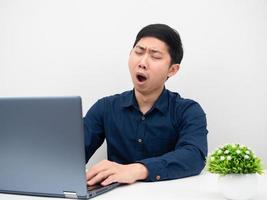 Man using laptop on the table yawn and feeling sleepy white background photo