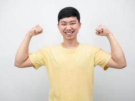 alegre hombre camisa amarilla mostrar músculo sonriente retrato foto