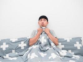 Man sitting on the bed cover blanket his body feeling fear photo