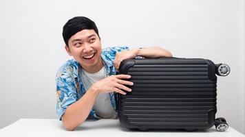 Cheerful man smiling hagging luggage looking above copy space photo