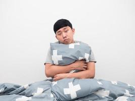 Man sitting on the bed hugging pillow feel sleepy and lazy photo