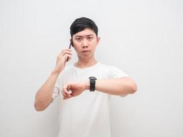 Asian man holding cellphone show his watch up serious face businessman concept photo