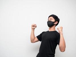 camisa negra de hombre asiático con máscara de doble puño hacia arriba y mirar hacia arriba sentirse feliz sobre fondo blanco aislado foto