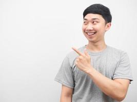 Asian man smiling grey shirt point finger at copy space photo