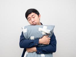 hombre asiático abrazo almohada sintiéndose somnoliento y perezoso para trabajar fondo blanco foto