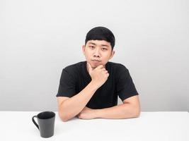 hombre asiático con taza de café en el retrato de pensamiento de gesto de escritorio foto