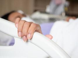Closeup hand of woman sick lay at hospital holding at rail bed photo