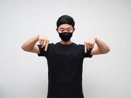 Asian man weraing mask point double finger and look down on white background photo