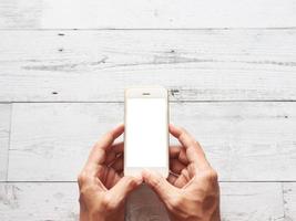 Hand using smartphone white screen on wood table top view space photo