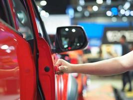 Hand opening the door of car red color event background photo