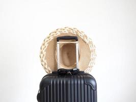 Vintage hat hanging above luggage black color on white isolated space,Holiday concept photo