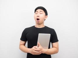 Asian man holding tablet feeling sleepy and yawn photo