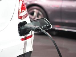 enchufe del vehículo de carga eléctrica en la batería de recarga en la parte trasera del enchufe del coche energía de energía limpia de color blanco para el concepto futuro foto