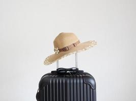 sombrero vintage sobre el color negro del equipaje en el espacio aislado blanco foto