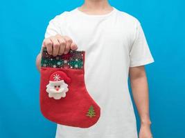 hombre sujetando calcetín de navidad tiro de cosecha fondo azul foto