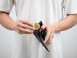 Man white shirt pick up golden bitcoin out of his wallet portrait photo