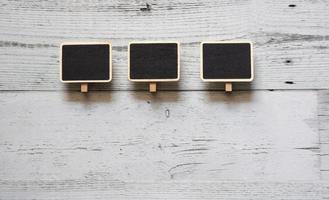 Three small clip chalkboard wood frame array line on white wood table top view nature shadow above space,Idea signboard concept photo